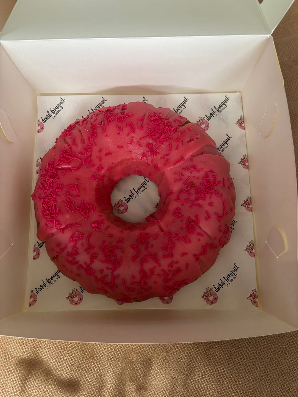 Donut Bouquet Canberra donut cake with bright pink icing and matching sprinkles in a branded white gift box